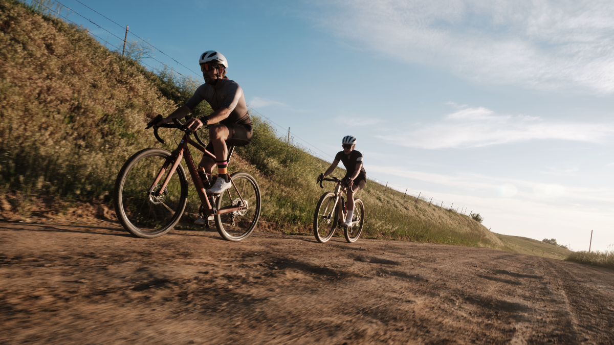 Get Better At Climbing Two Gravel Cyclists Climbing Uphill Outside