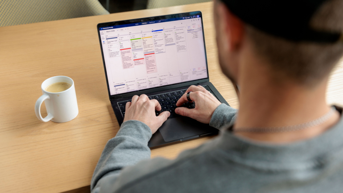 Trainingpeaks Coach Creating Training Plan In Trainingpeaks Store Sitting At Desk On Laptop