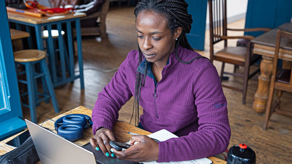 a female coach working in TrainingPeaks at a computer with a GPS device in-hand
