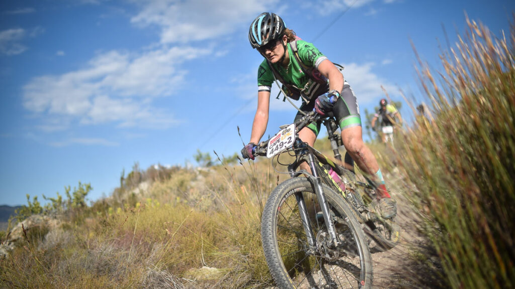 female MTB cyclist rides down a trail at the 2017 Absa Cape Epic