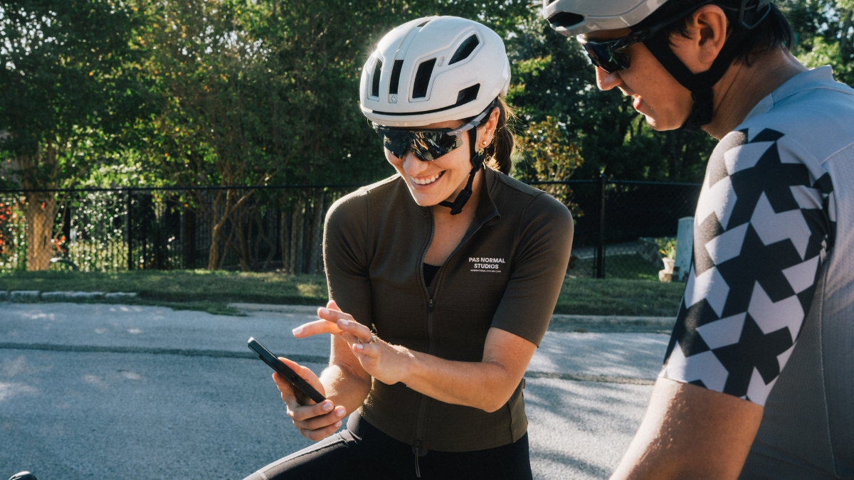 Find Athletes Authentically Athlete And Coach Looking At Traininngpeaks Data In Phone On Bikes Together
