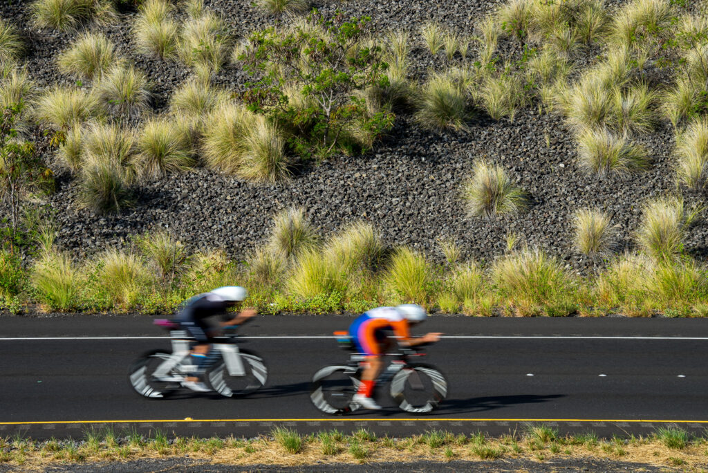 two cyclists riding on the road during a triathlon race in Hawaii