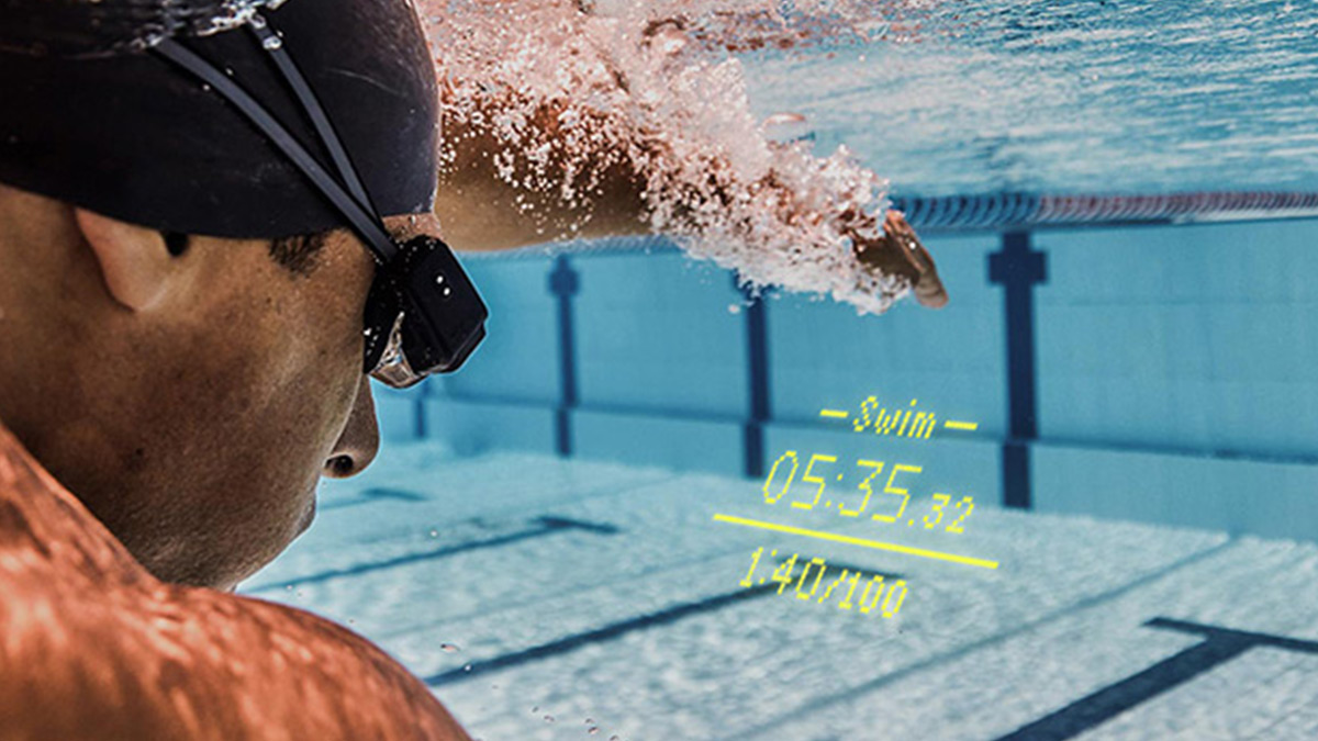 Swimmer In The Pool Underwater. Wearing Form Goggles, The Workout Is Showing In The Water.