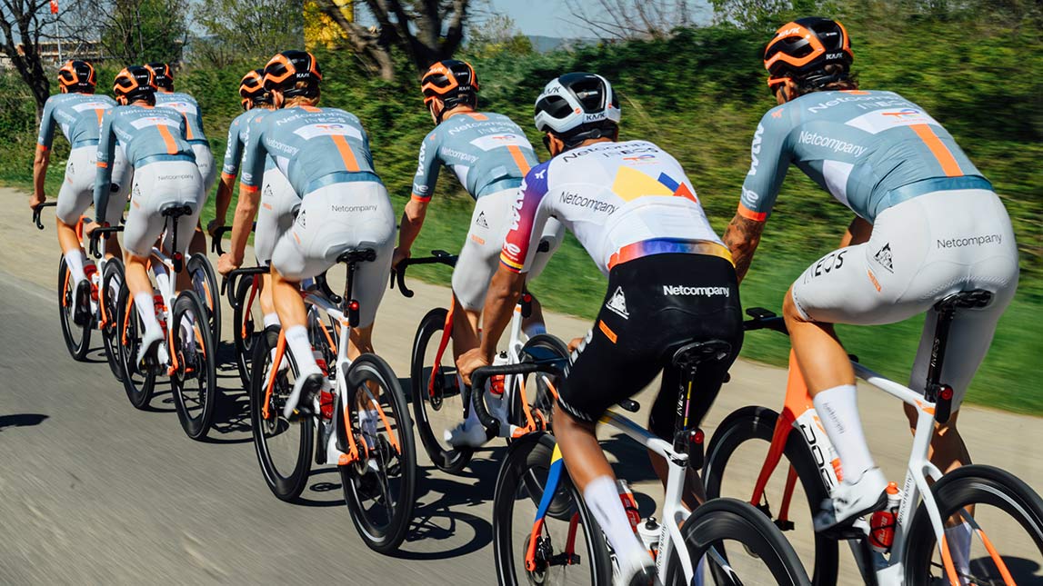 Netcompany Ineos Cycling Team And Trainingpeaks Male Cyclists Riding In Tight Pack Up Country Road Netcompany Ineos Cycling Team And Trainingpeaks