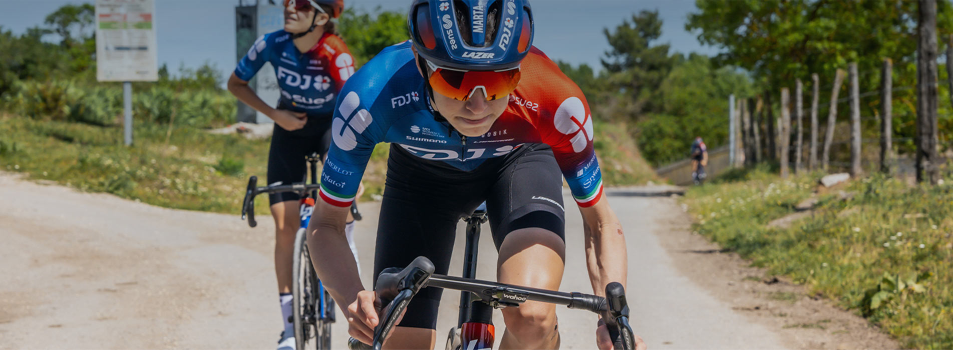 Female Professional Cyclists Riding Up Mountain Road