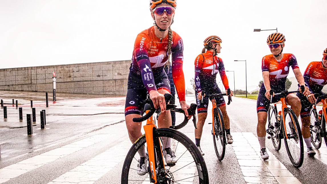 Female Cyclist Trackstand In Front Of Team