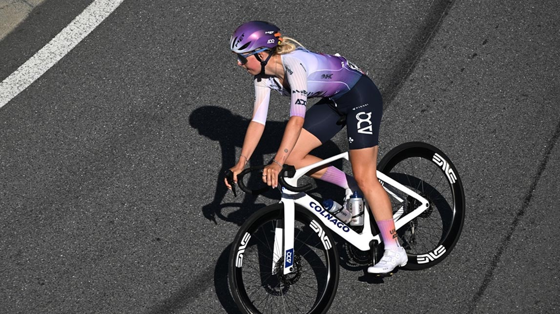 Trainingpeaks And Uae Adq Female Cyclist Making A Right Turn On Smooth Asphalt From Team Uae Adq