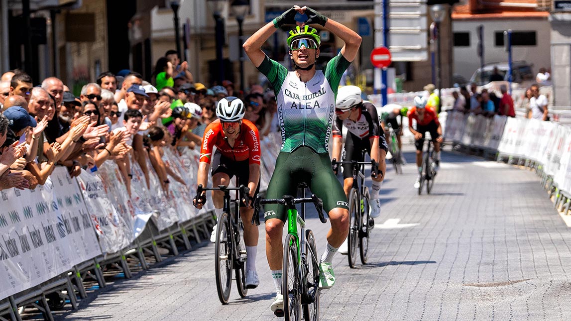 Trainingpeaks And Caja Rural Seguros Rga Male Cyclist From Team Caja Rural Seguros Rga Crossing The Finish Line First And Making A Heart With Hands