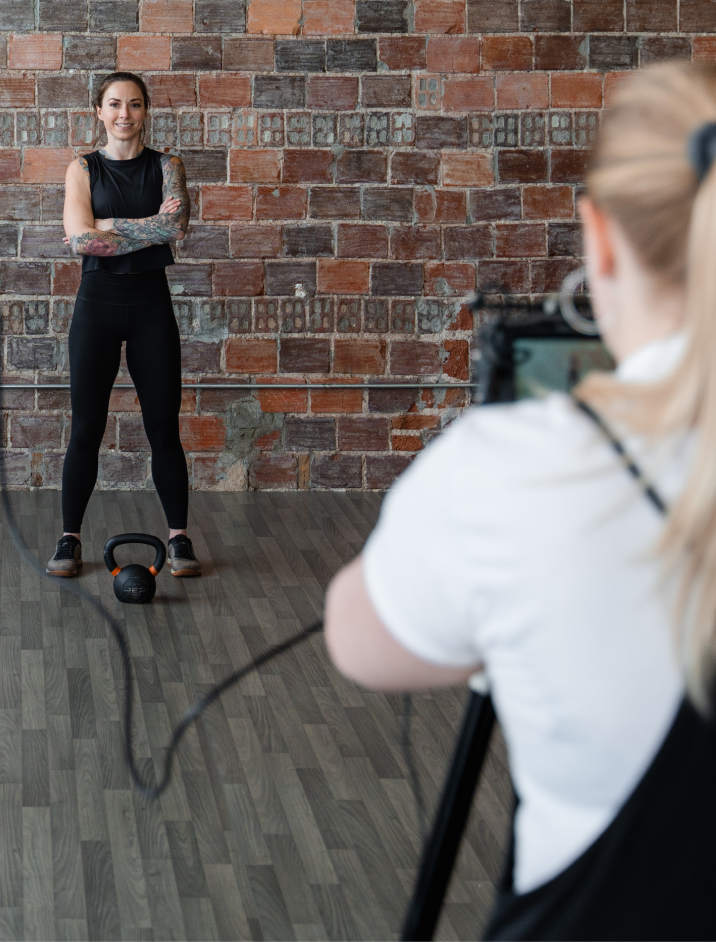 Videographer Filming Strength Athlete In Brick Walled Gym