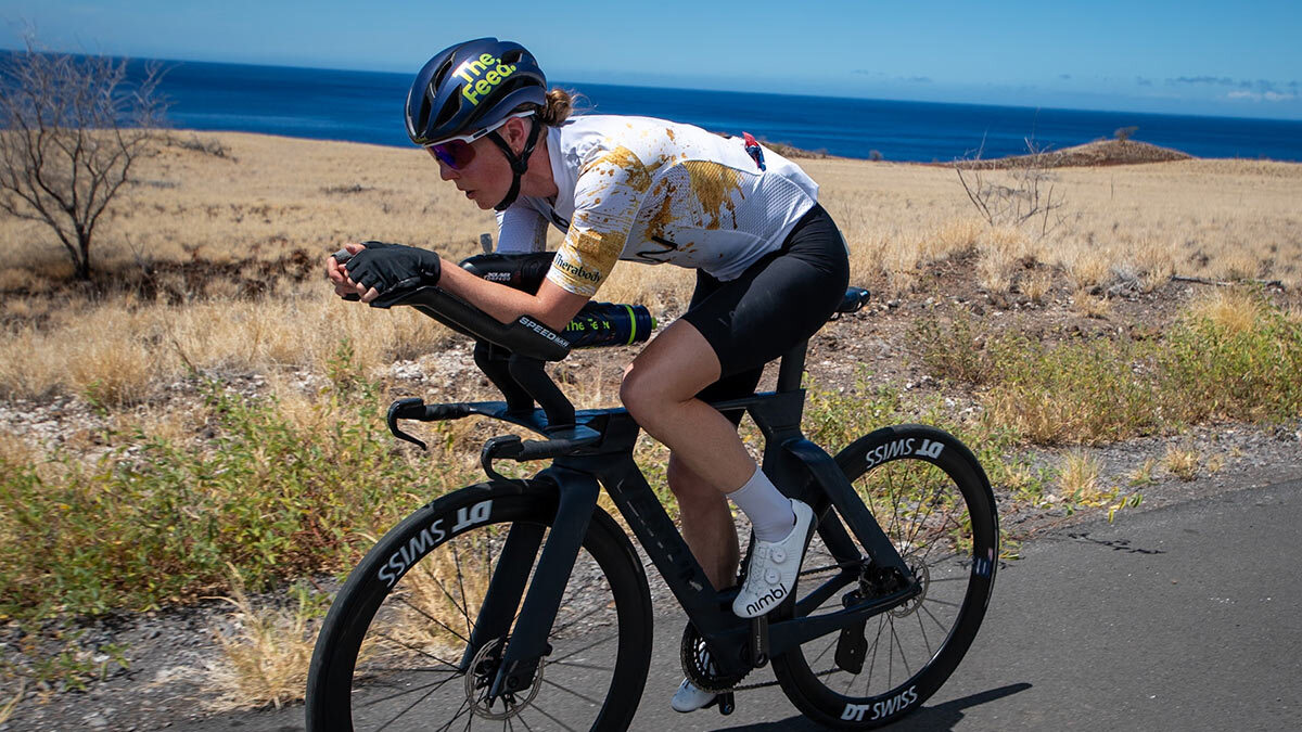 Image Of Ironman World Champion Chelsea Sodaro Cycling On A Paved Road In Front Of The Sea At A Kona Training Camp
