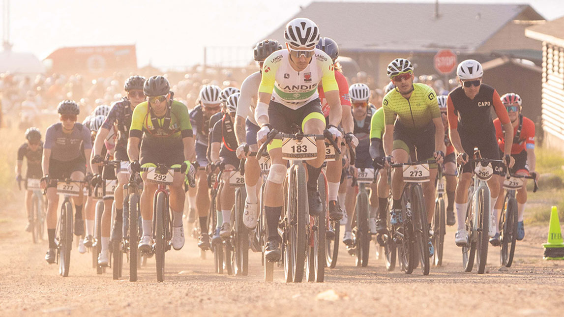 Large Pack Of Male Gravel Cyclists Racing Up Dirt Road