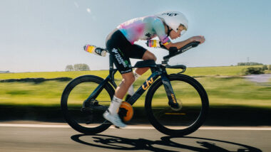 Female cyclist riding time trial bike down country side road - Lizzie Rayner