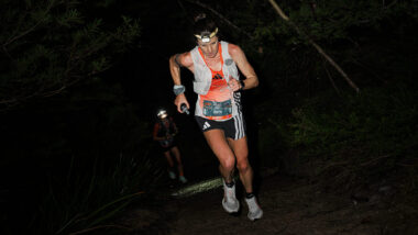 Female Trail runner climbing hill in the dark during UTMB race - Photo by Phillip Sage