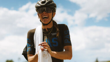 Female triathlete, Anna Gibson, posing for photo next to bike