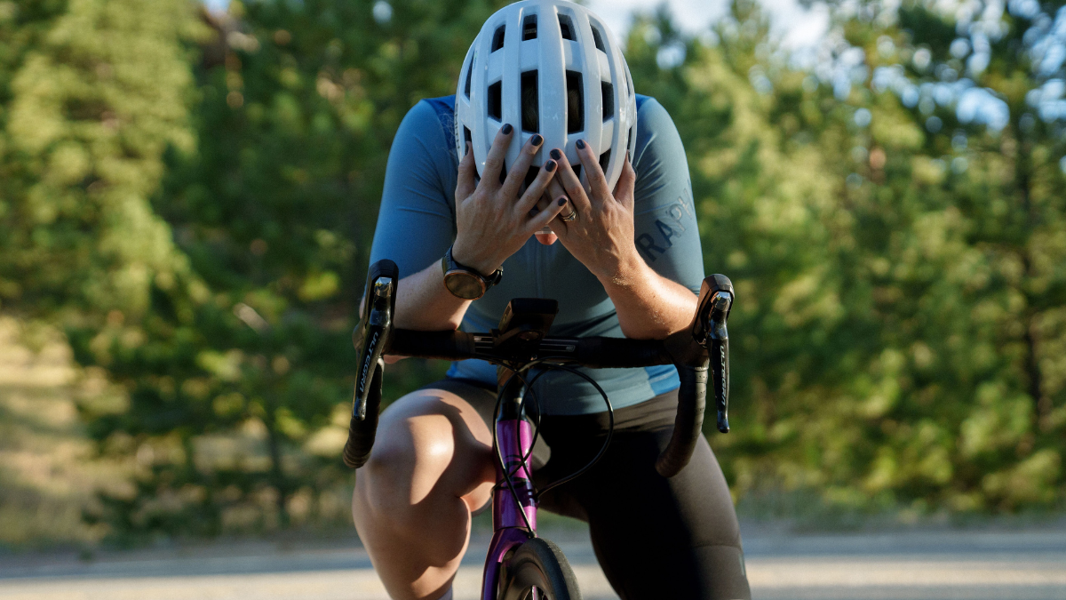 What Durability Data Doesn’t Tell Us Cyclist Standing Over Her Bike After A Hard Ride, With Her Head Down And Hands On Her White Helmet.